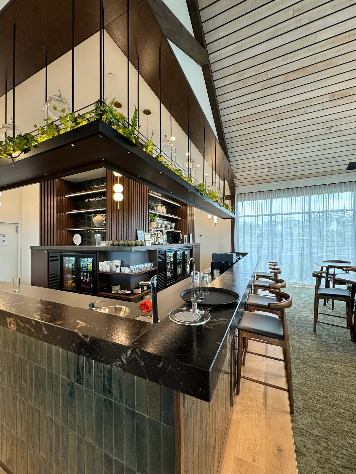 Commercial stone bar counter with integrated sinks, tiled front and timber seating