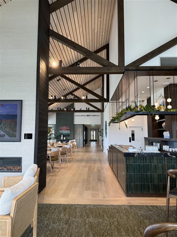Full-height view through the Arvida clubhouse showing timber ceiling, bar joinery and dining area