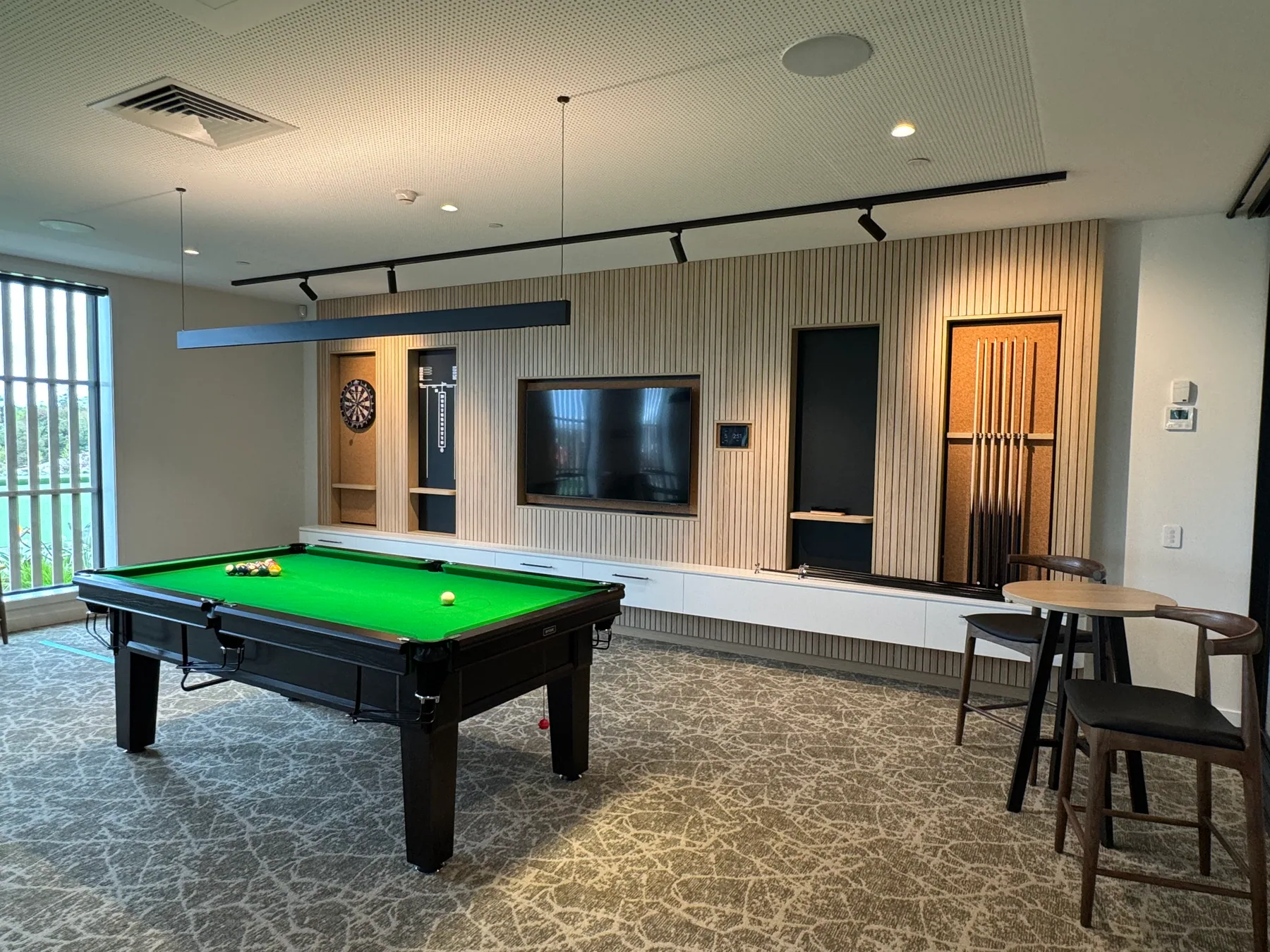 Arvida games room with full-width slatted timber media cabinetry and cue storage
