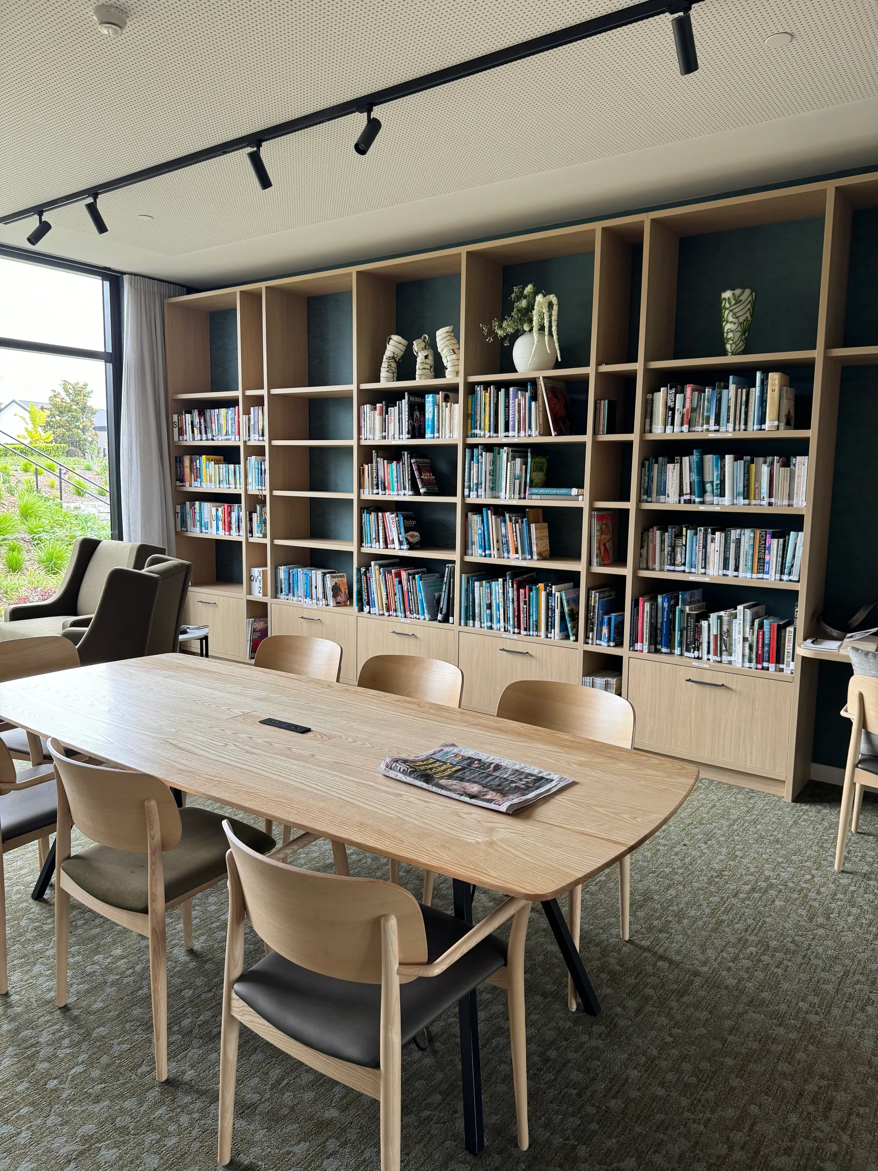 Arvida library with full-height custom shelving, display niches, storage drawers and communal table