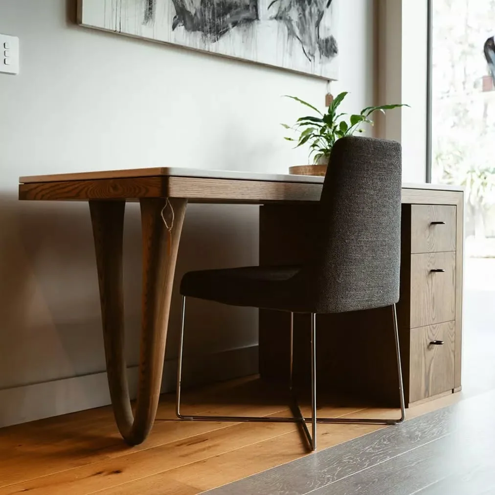 Custom timber desk with sculpted legs, integrated drawers and a clean wall-to-wall fit