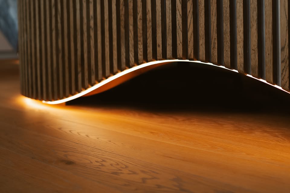 Curved timber-slat commercial joinery with concealed warm LED lighting