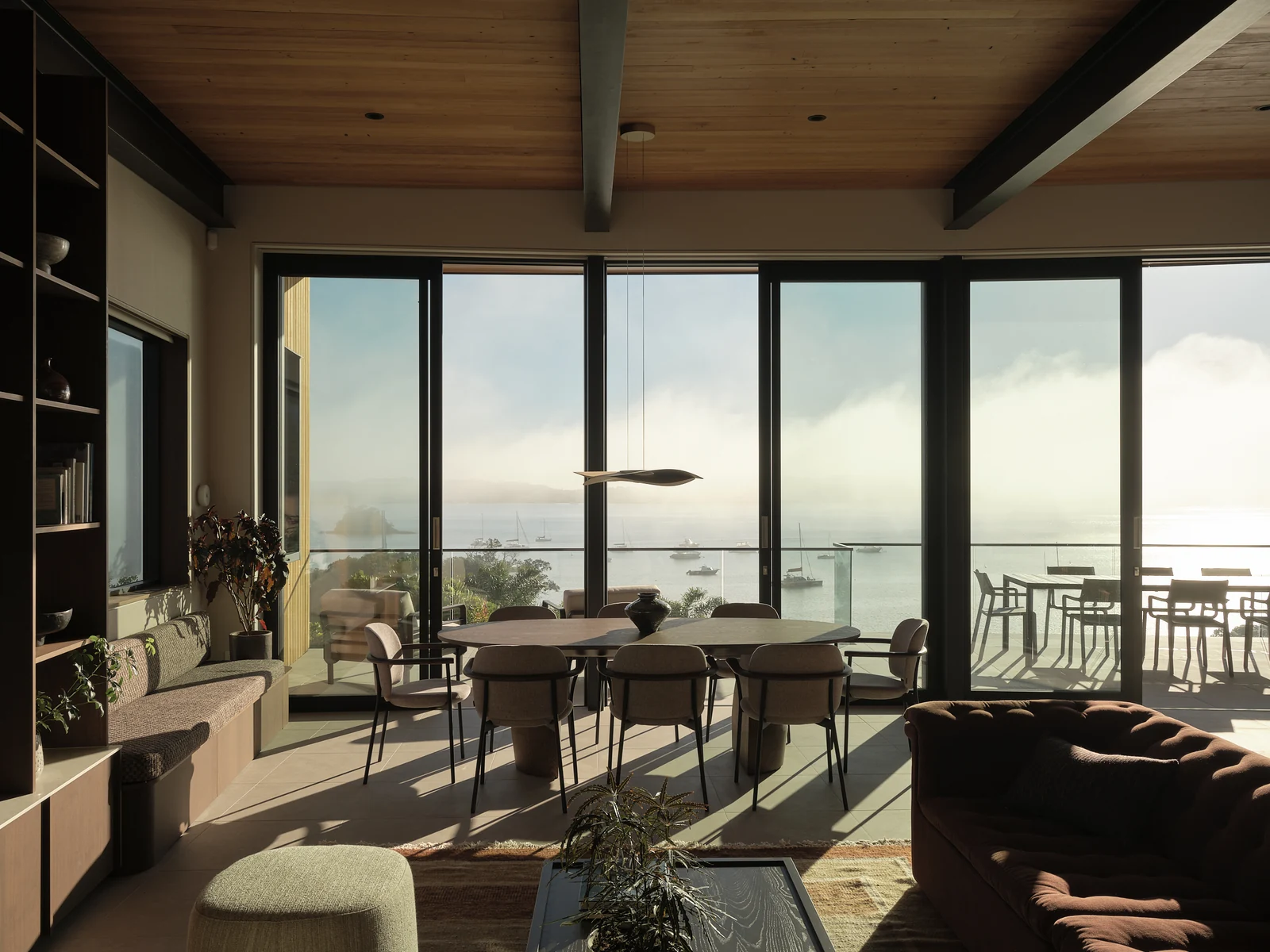Dining table, living area and window seat facing the Bay of Islands in morning sunlight