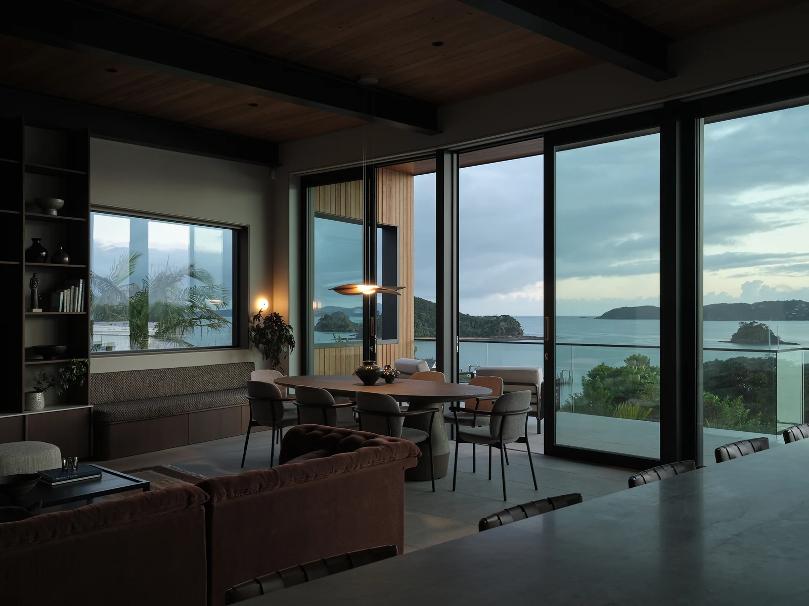 The dining area and window seat at dawn with the pendant and wall light glowing
