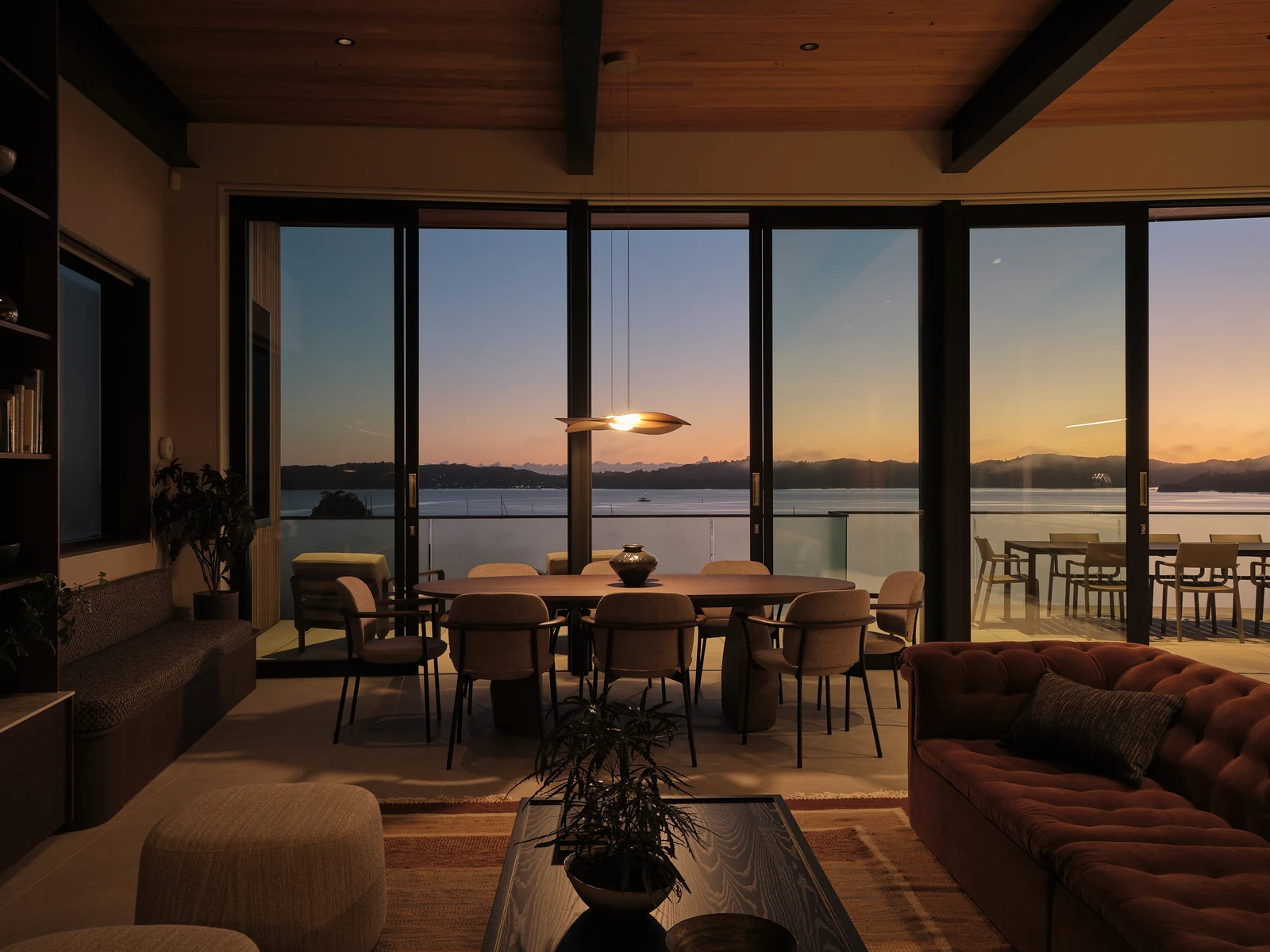 The same dining and living space before dawn, with the island pendant illuminated