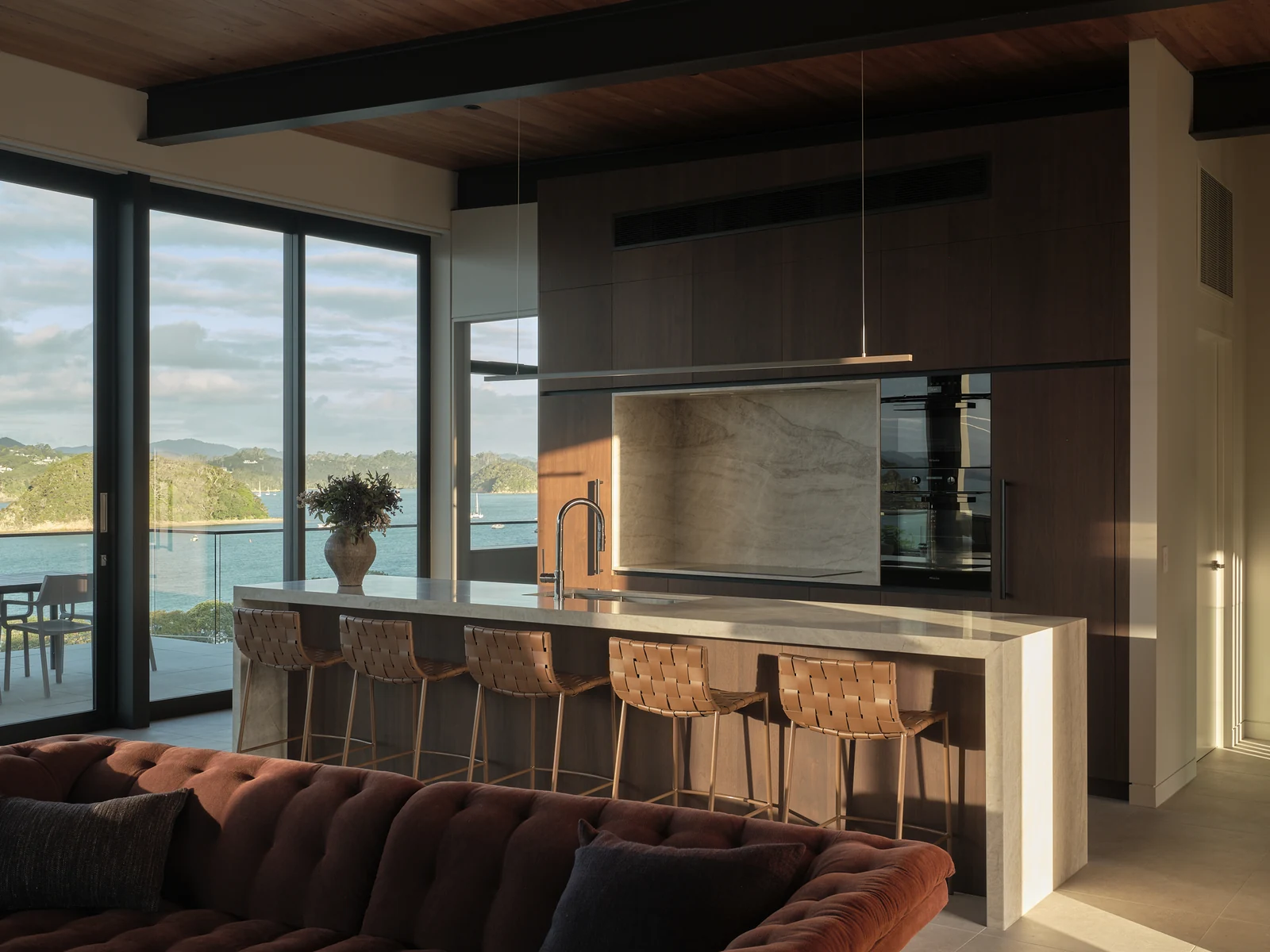 Late afternoon sun on the kitchen island and walnut cabinetry seen from the living room