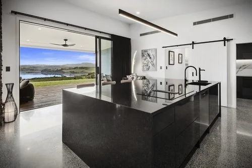 Black island kitchen opening directly to a wide Northland water view