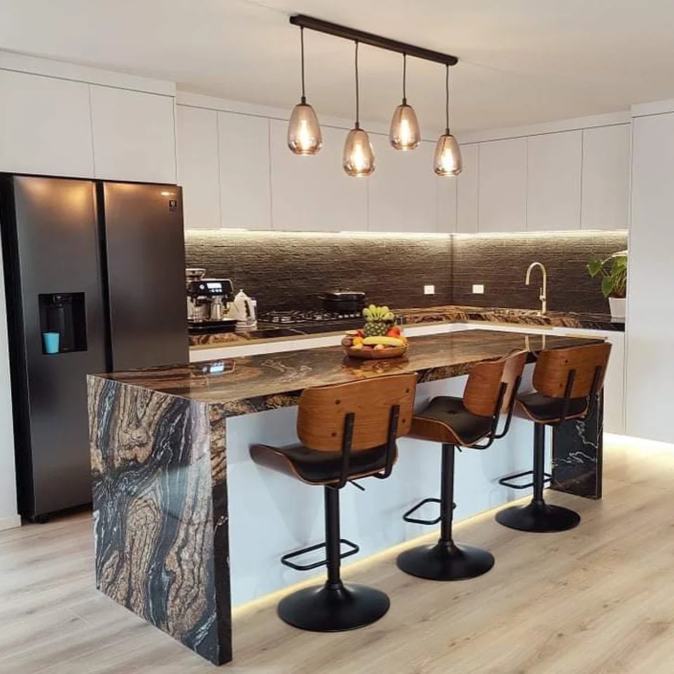 White kitchen with a richly patterned stone waterfall island, timber seating and pendant lighting