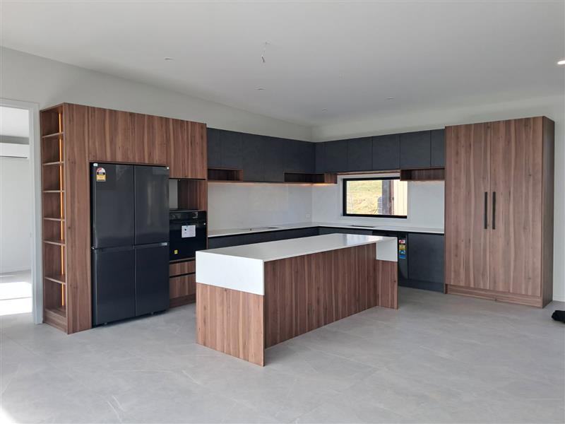 Walnut and charcoal kitchen with waterfall island and full-height pantry cabinetry