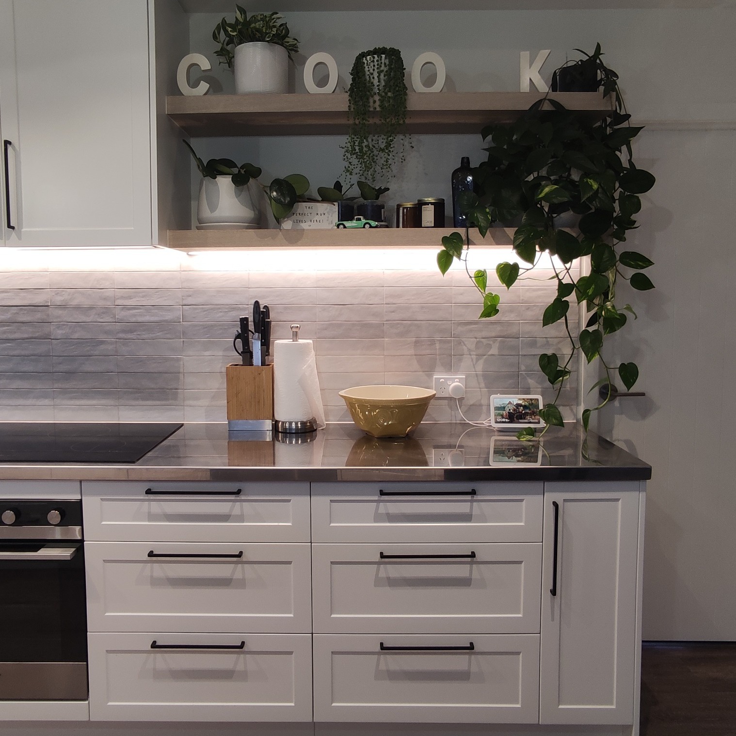 White Shaker kitchen drawer run with black handles, open shelf and task lighting