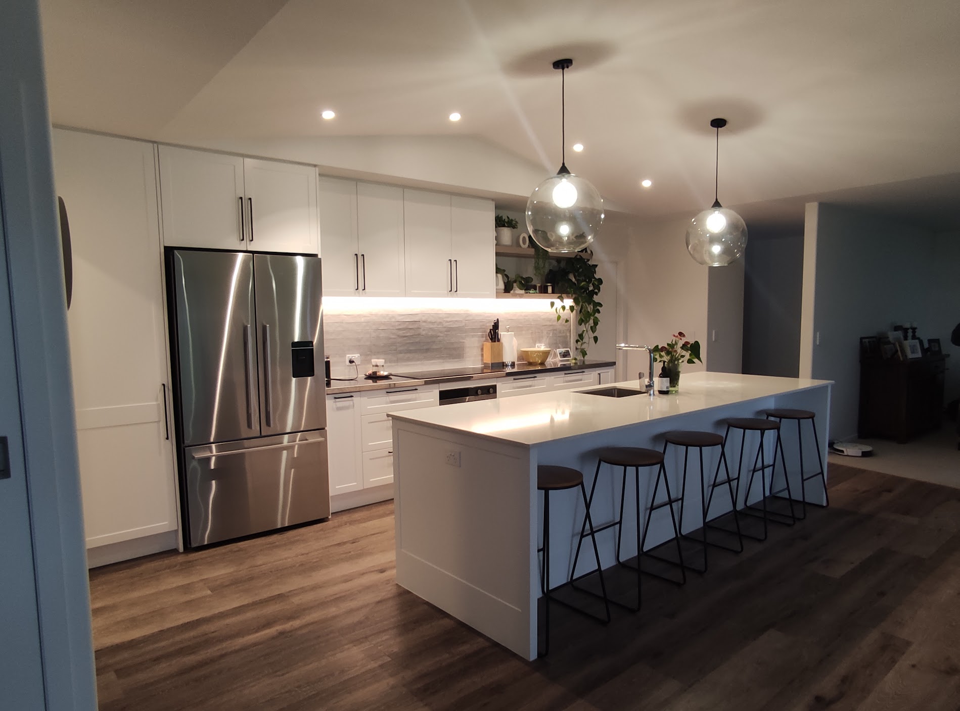 White Shaker kitchen with a generous island, seating and integrated storage by North Interiors