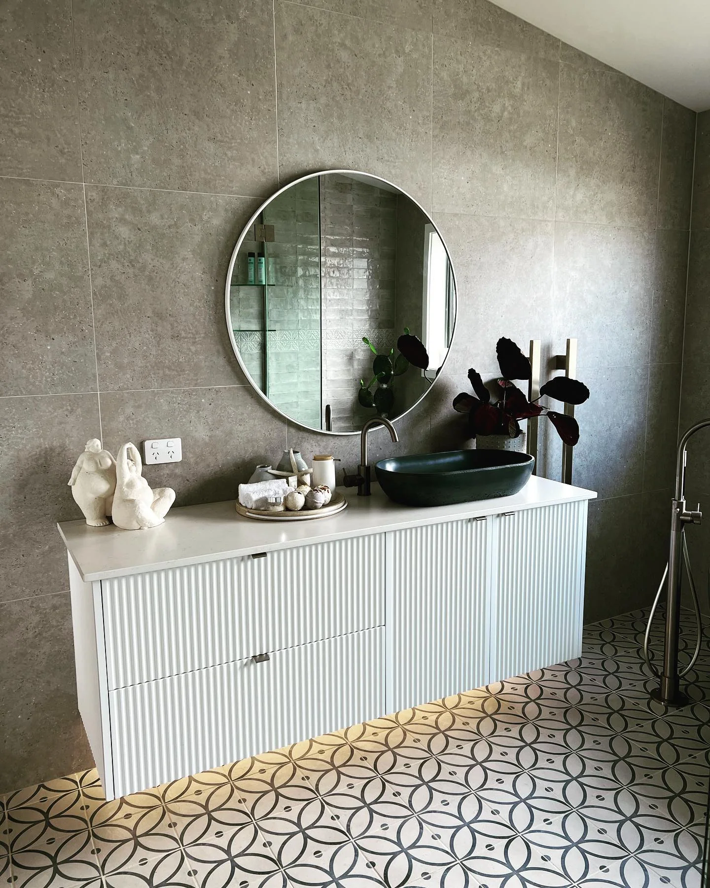 Fluted wall-hung wet-area cabinetry with integrated drawers, green basin and round mirror