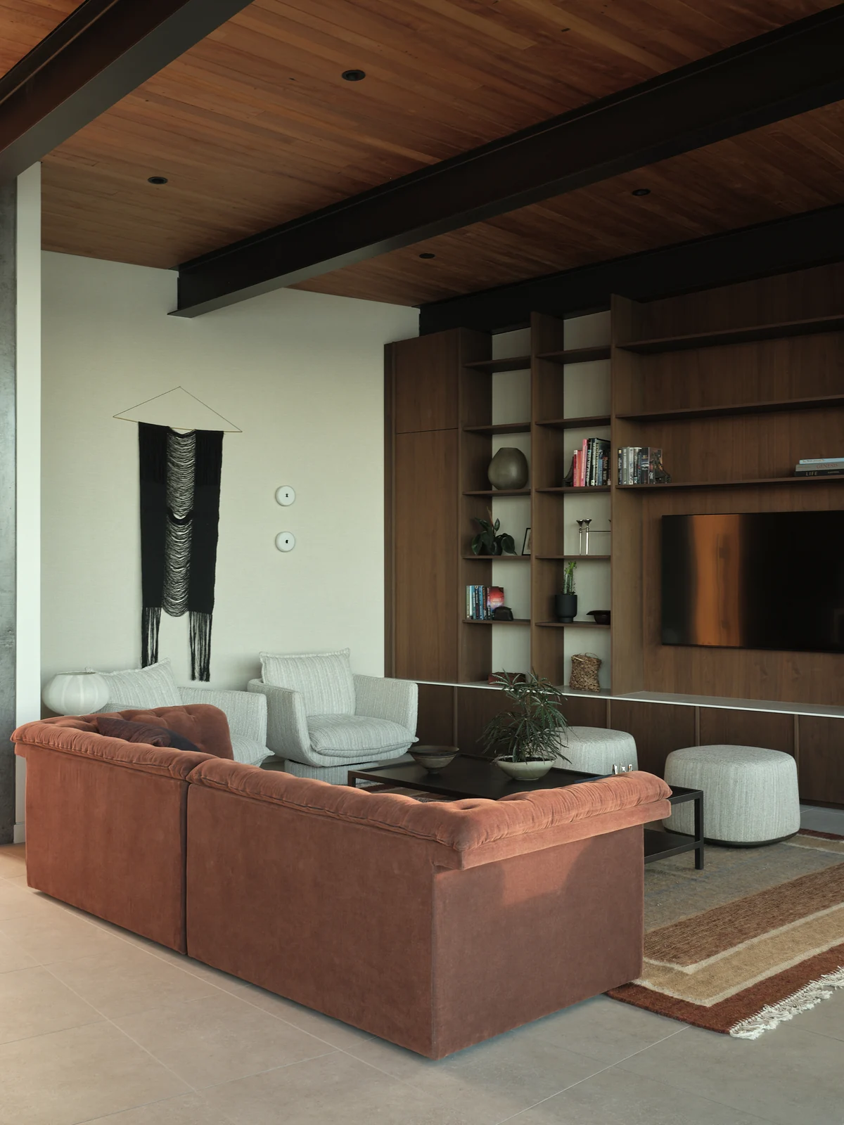 Walnut television wall, open shelving and window seat beside the School Road living area in daylight