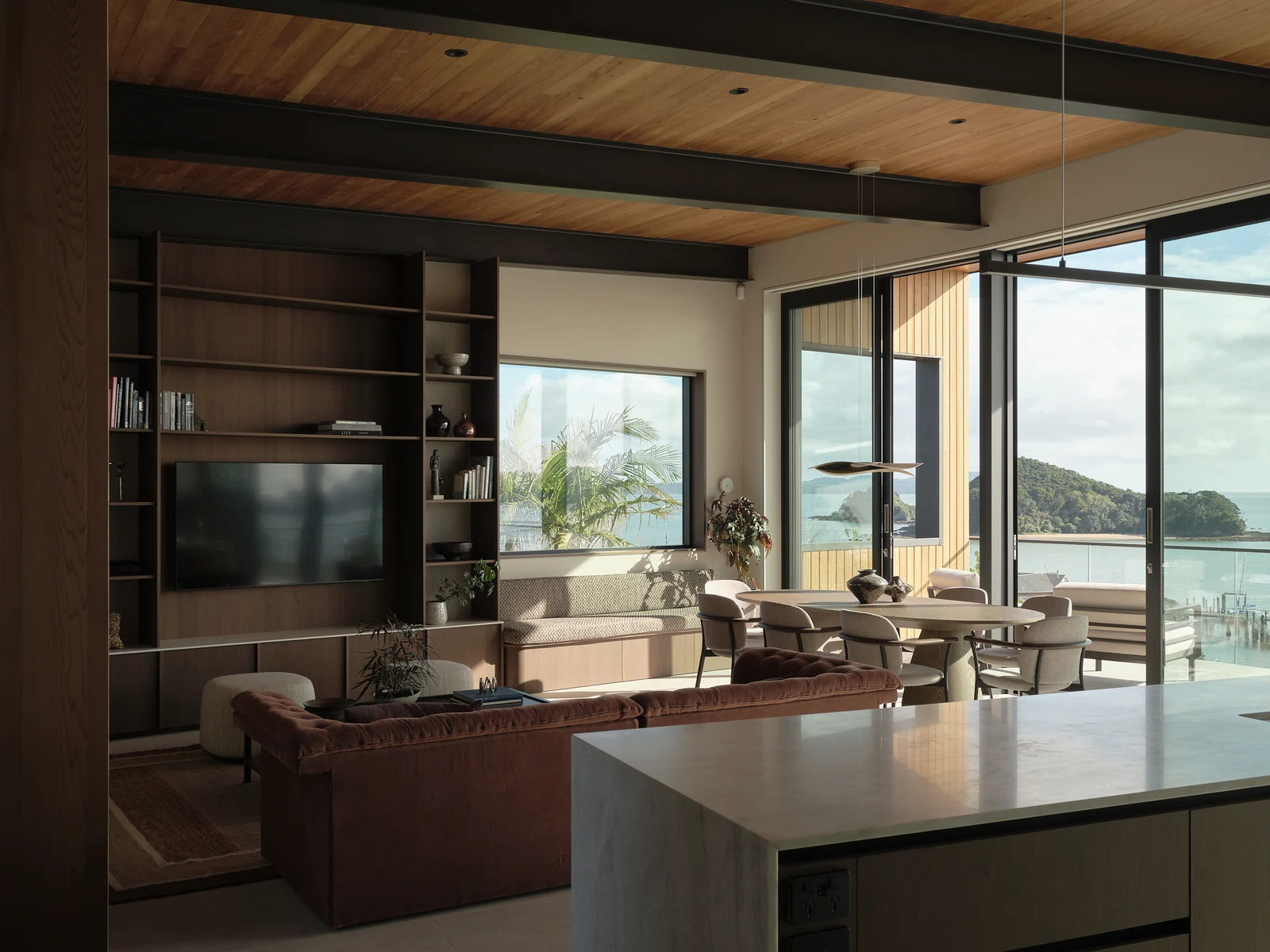 Morning light across the living room, display wall and dining area seen over the kitchen island