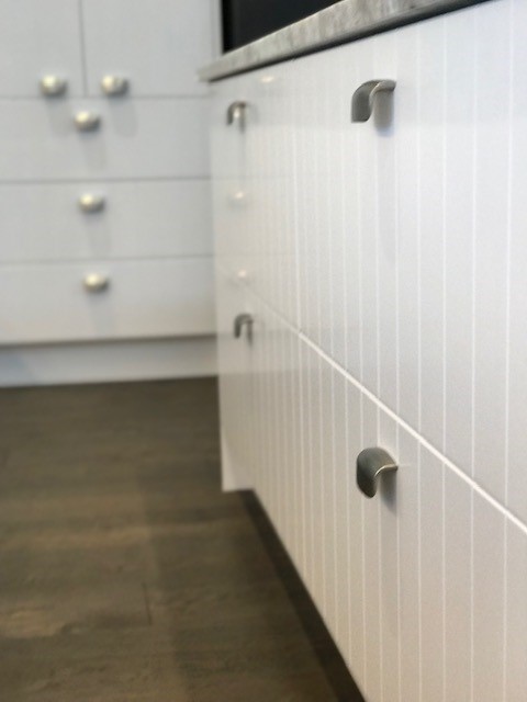 Close detail of brushed metal handles on white custom scullery drawers