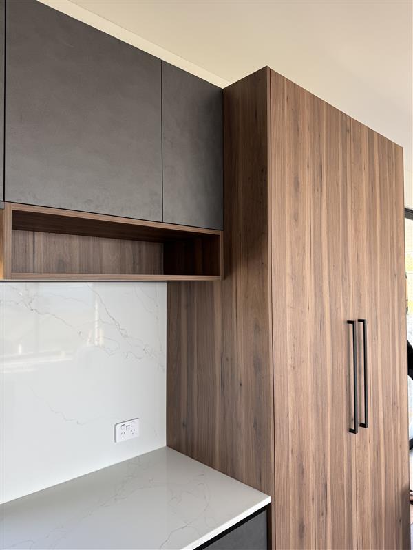 Walnut pantry cabinetry, stone benchtop and dark overhead cupboards in a custom scullery