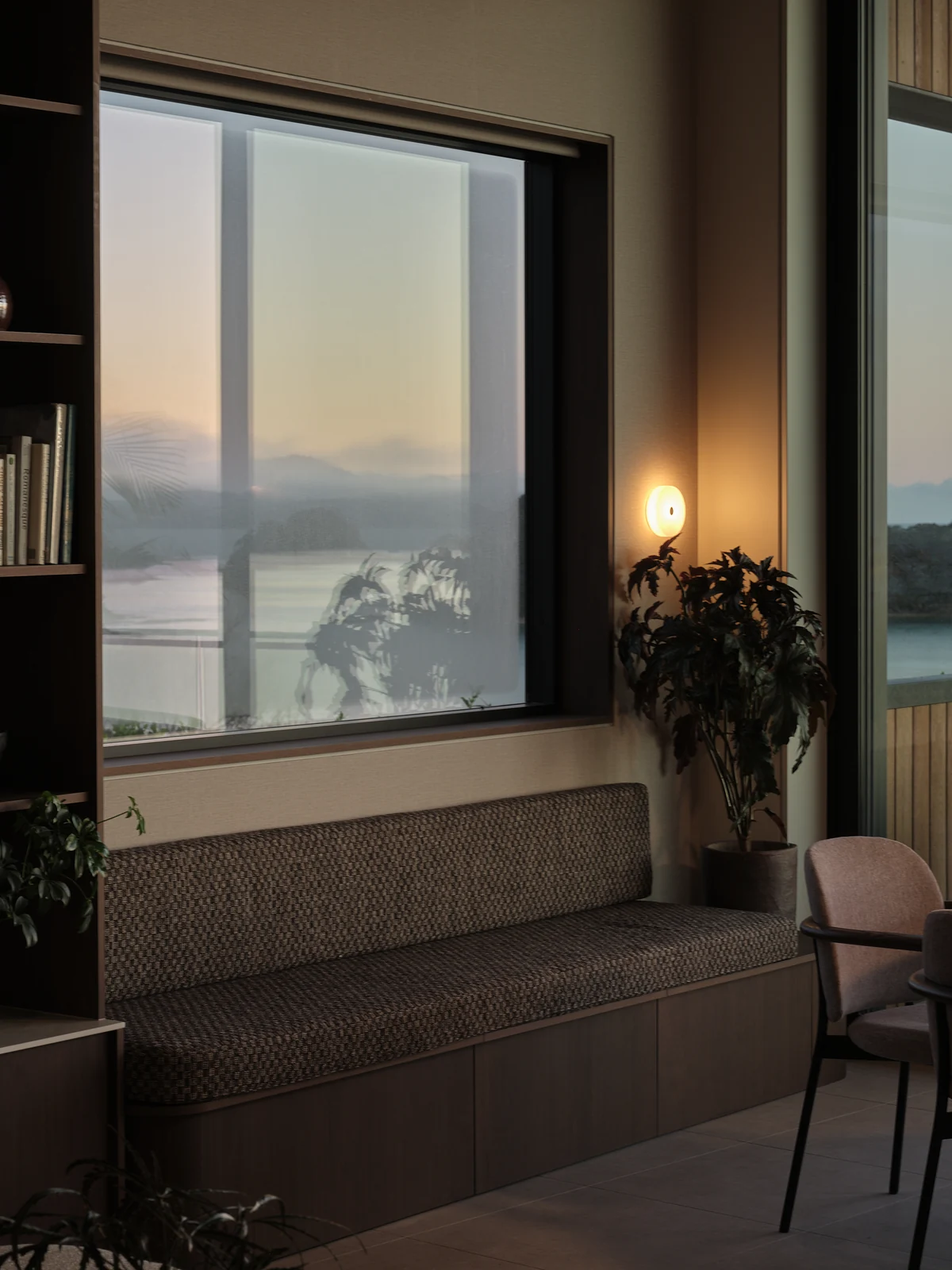 A wider view of the upholstered window seat and timber base at dawn beneath the illuminated wall light