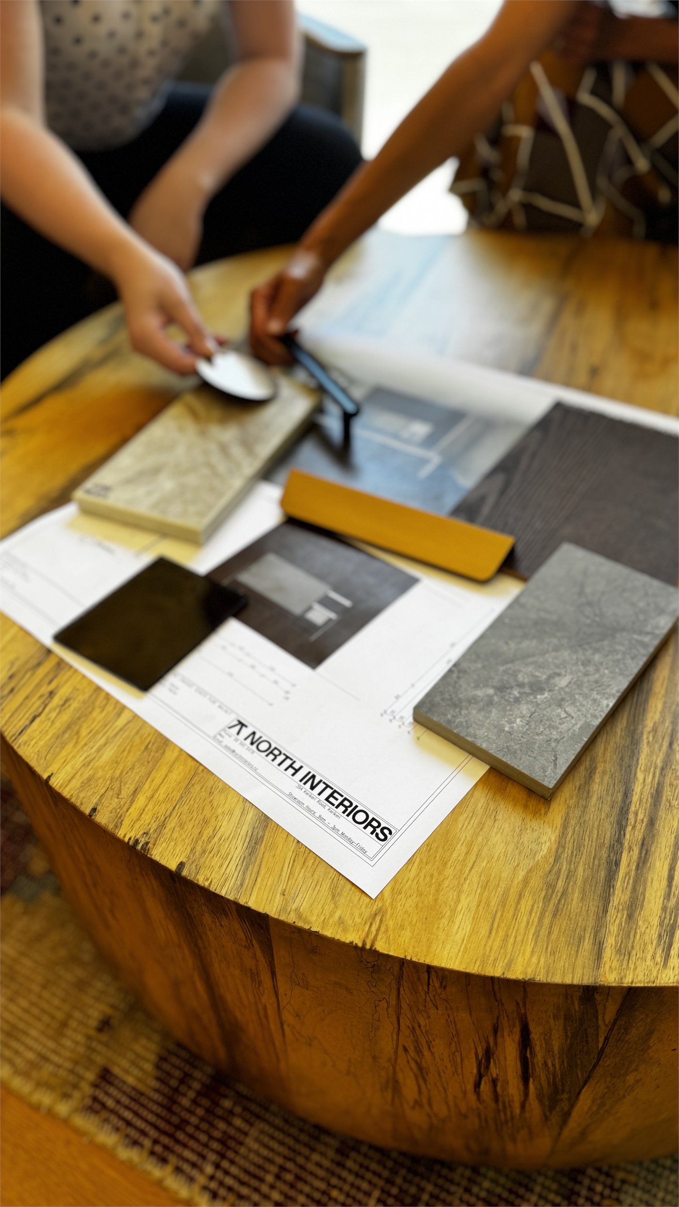 North Interiors designers comparing material, hardware and colour samples over cabinetry plans